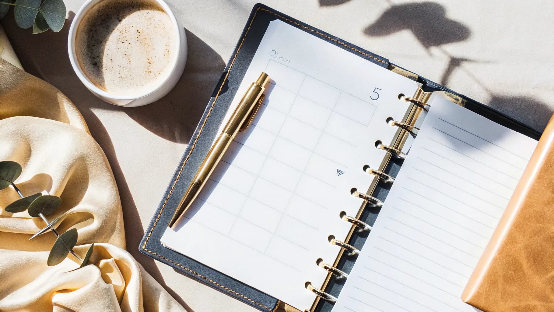 An open wedding planner with a checklist and a gold pen on a sunlit table